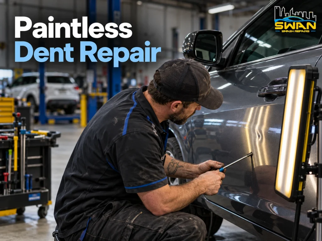 Technician performing paintless dent repair on a car panel using specialist PDR tools in a smash repair workshop.
